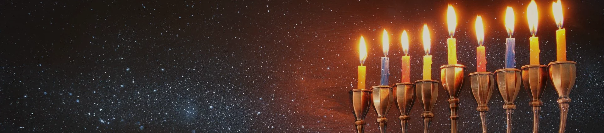 Menorah candles illuminated against a nocturnal scene